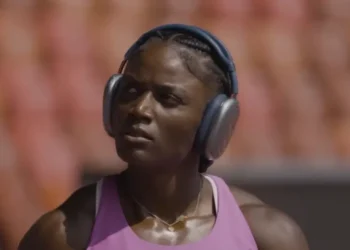 Julien Alfred road to Tokyo captured in focus as she prepares on the track wearing headphones and training gear.