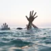 Hands struggling above the water during a drowning incident, illustrating a case where St Lucia police probe suspected drowning at Five Dollar Beach in Cas En Bas.