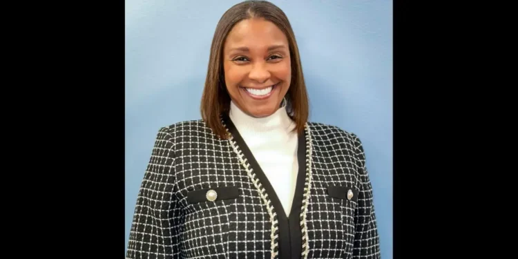 Teri Helenese urges sustainable tourism growth in a professional portrait wearing a black-and-white blazer against a light blue background.