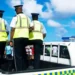 Police officers standing in a patrol vehicle during a daytime operation related to Customs employees arrested in St Lucia.