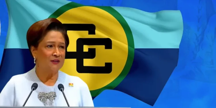 Kamla Persad-Bissessar speaking at a podium with the Caricom flag behind her as she says Caricom dysfunctional
