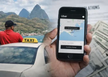 A licensed taxi driver in St Lucia beside his vehicle while a smartphone displays the Uber app during Uber registration in St Lucia.