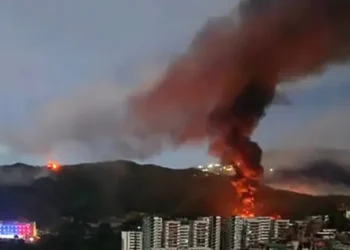 Fire and smoke rise over Caracas following reports linked to the US strike in Venezuela.