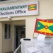 Grenada electoral system failure context shown outside the Parliamentary Elections Office with a ballot box and Grenada flag in the foreground