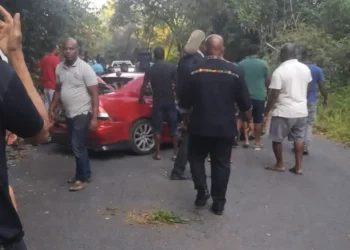 Serious accident at Ladera Gap as bystanders gather around a damaged red vehicle following a traffic crash in Soufrière