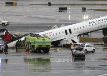 LaGuardia crash scene showing damaged Air Canada Express plane on runway with emergency crews