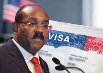 Gaston Browne urges US visa caution in a composite image showing the prime minister beside a close-up of a US visa page with a blurred American flag in the background.