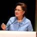 Prime Minister Kamla Persad-Bissessar speaks at a podium as Trinidad Declares State of Emergency