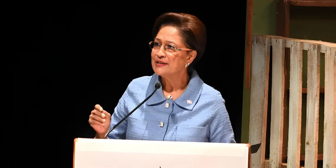 Prime Minister Kamla Persad-Bissessar speaks at a podium as Trinidad Declares State of Emergency