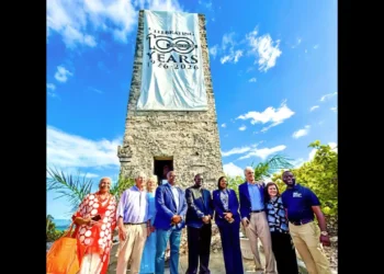 Blue Lagoon Watch Tower 100th Anniversary ceremony in Nassau Bahamas with officials gathered beneath the historic tower and commemorative banner