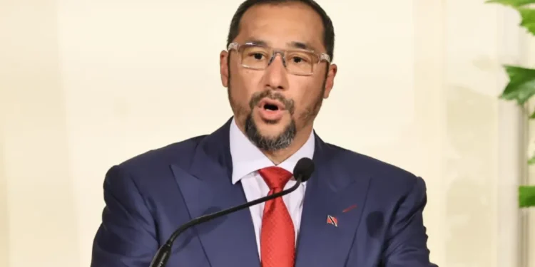 Stuart Young Record article features Stuart Young speaking at a podium in a blue suit, red tie and glasses