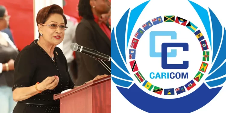 Kamla Persad-Bissessar speaking at a podium alongside the Caricom logo representing the T&T defies Caricom reappointment dispute.
