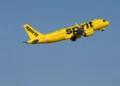 A Spirit Airlines aircraft climbs after takeoff against a clear blue sky, May 2026.