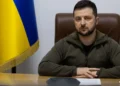 Ukrainian President Volodymyr Zelenskyy seated at a desk with the Ukrainian flag behind him, addressing the Romanian Parliament amid the EU associate membership dispute.