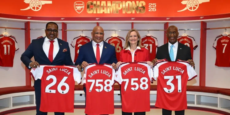 Arsenal deal officials hold Saint Lucia jerseys inside Emirates Stadium dressing room at partnership signing