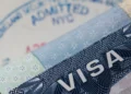 A U.S. visa document and entry stamp illustrating U.S. visa revocations tied to fraud and Medicaid abuse
