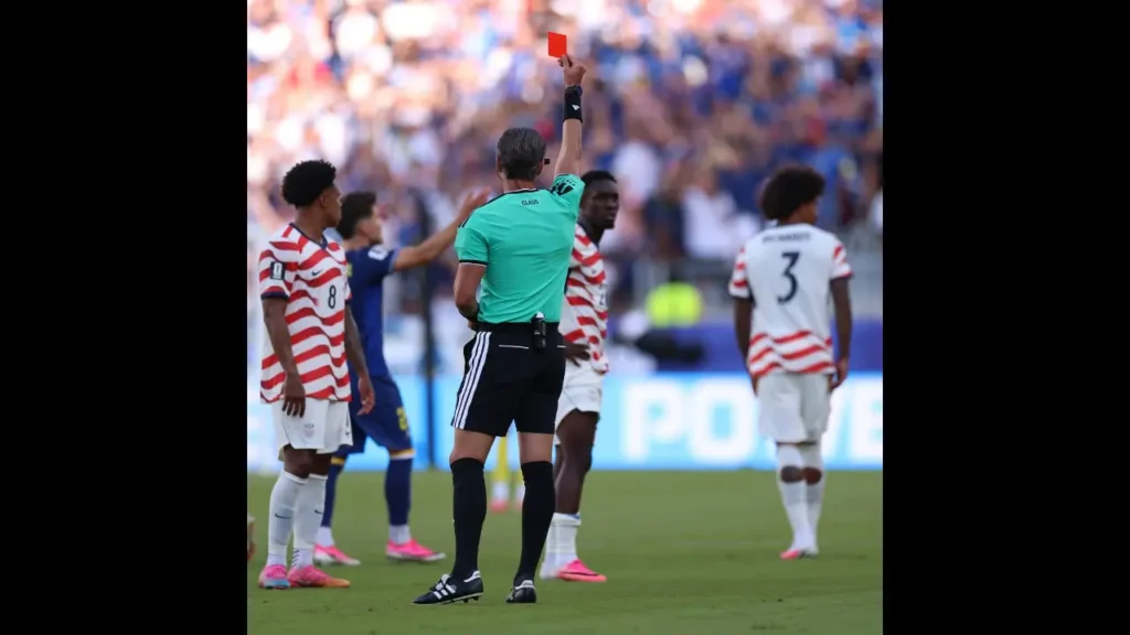 A referee holds up a red card as USMNT players react during a 2026 World Cup match.