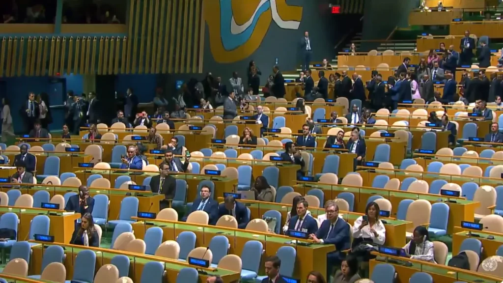 Delegates stand in the aisles and sit at desks in a partly empty UN General Assembly hall during the walkout during Netanyahu's address.