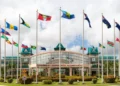 CARICOM Secretariat headquarters in Georgetown, Guyana, with national flags flying outside the building, representing CARICOM free movement and regional integration.