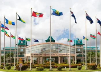 CARICOM Secretariat headquarters in Georgetown, Guyana, with national flags flying outside the building, representing CARICOM free movement and regional integration.