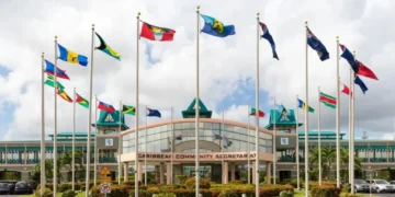 CARICOM Secretariat headquarters in Georgetown, Guyana, with national flags flying outside the building, representing CARICOM free movement and regional integration.