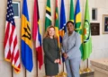 Grenada Opposition Leader Emmalin Pierre stands with a US diplomat beside Caribbean and US flags.