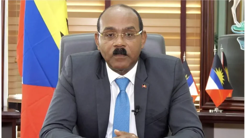 Antigua and Barbuda Prime Minister Gaston Browne seated at his desk with national flags behind him.