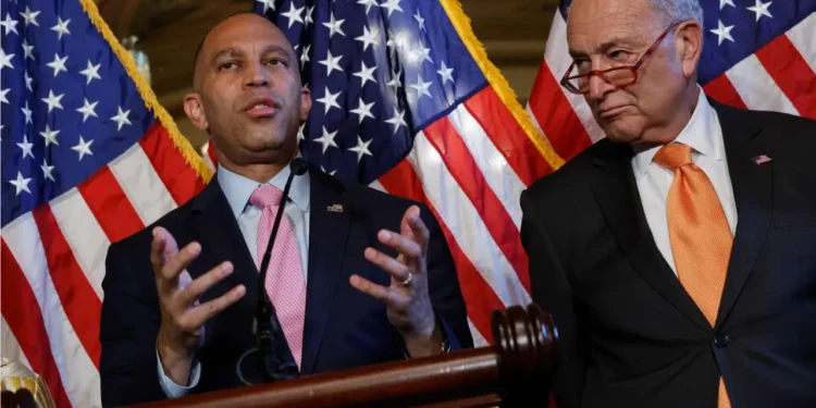 Hakeem Jeffries speaks beside Chuck Schumer with U.S. flags behind them, pictured in coverage of the lawsuit challenging voter purge demands.