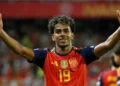 Lamine Yamal celebrates with both arms raised while wearing Spain’s red jersey.