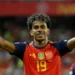 Lamine Yamal celebrates with both arms raised while wearing Spain’s red jersey.